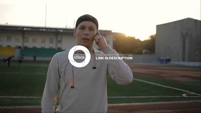 'young fitness man talks on the phone on stadium track in slow motion'