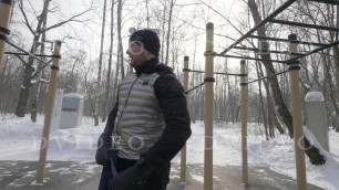 'Fitness man using expander for outdoor training on sports ground in winter park.'