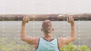 'Athlete man lifting weight by wooden barbell while outdoor training. Fitness man doing press'