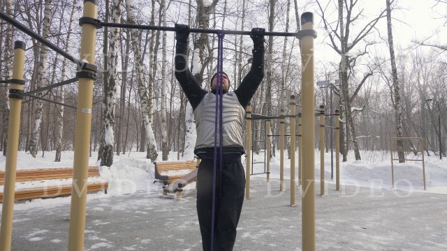 'Fitness man training pull up exercise on sport ground. Outdoor winter training'